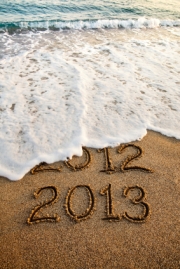 Wave erasing 2012 written on the sand with 2013 on foreground